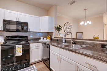 A kitchen with white cabinets and black appliances